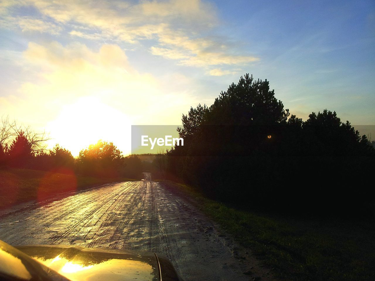 Cropped image of car on road against sky at sunset