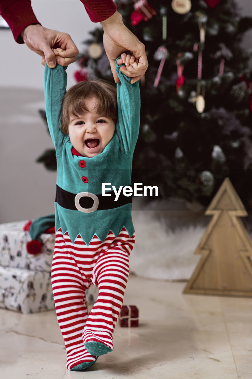 A little 12-month-old christmas elf with a christmas tree and gifts