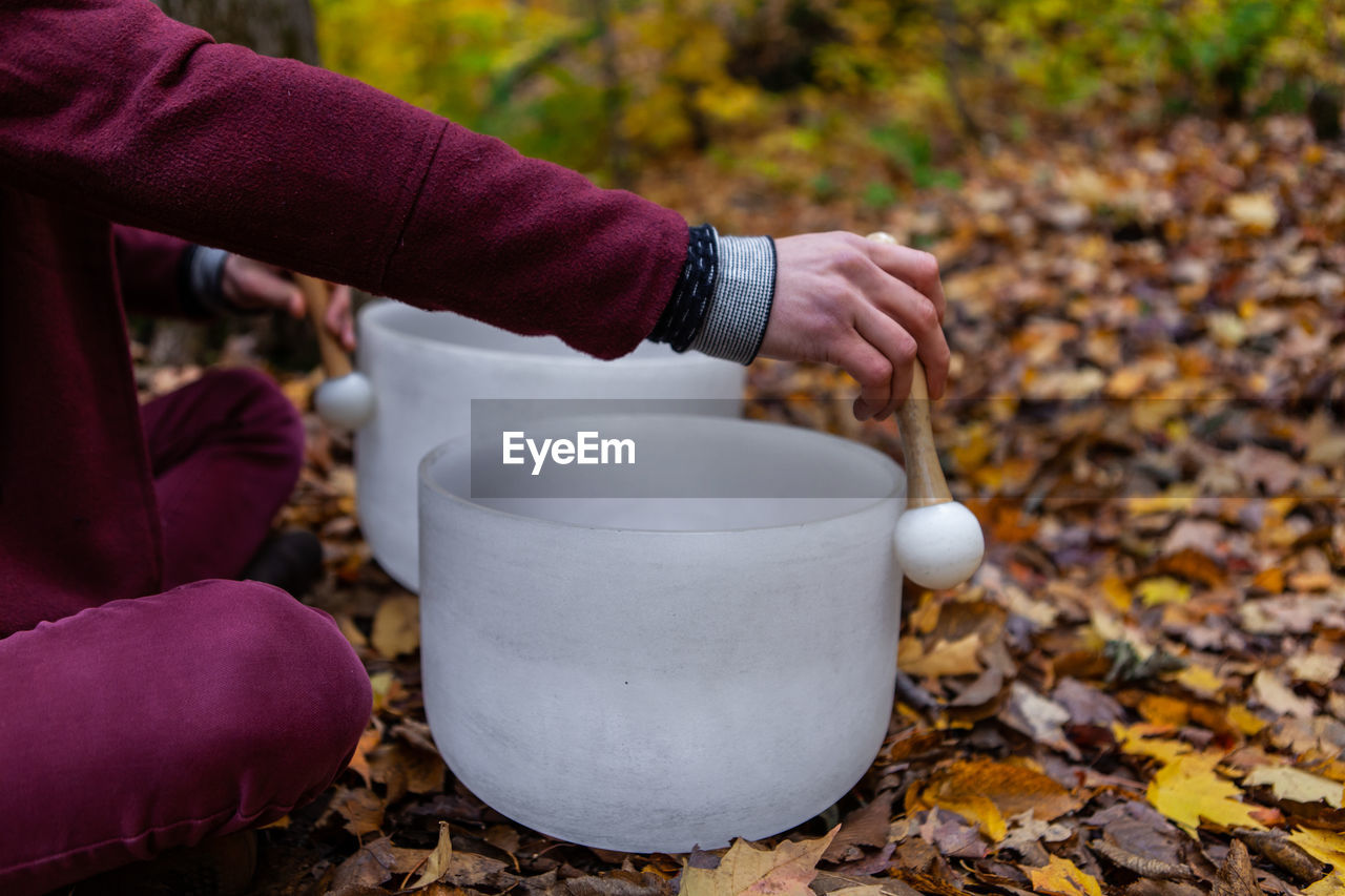 Midsection of man playing singing bowl outdoors