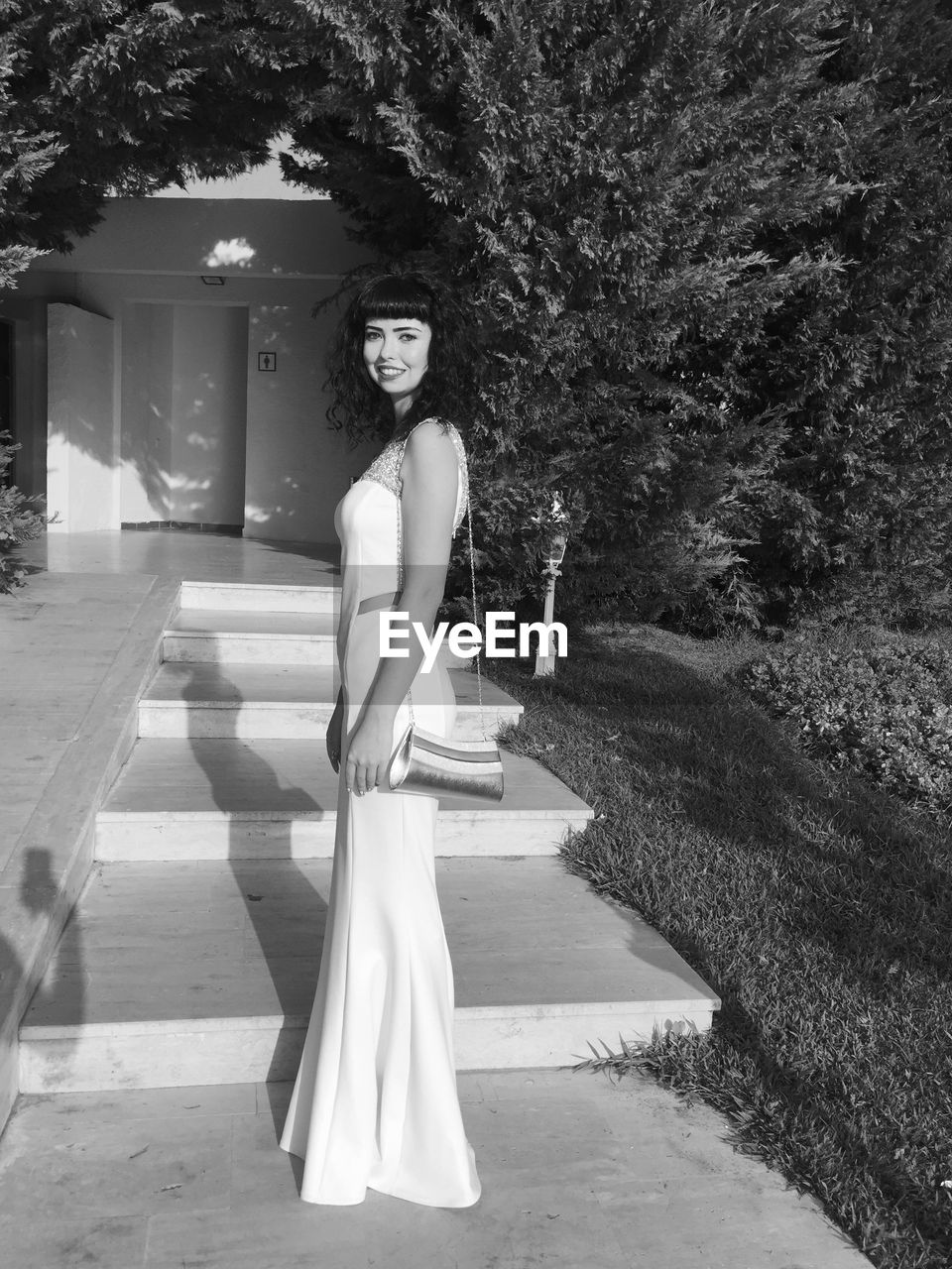 Portrait of smiling woman standing on steps leading towards house