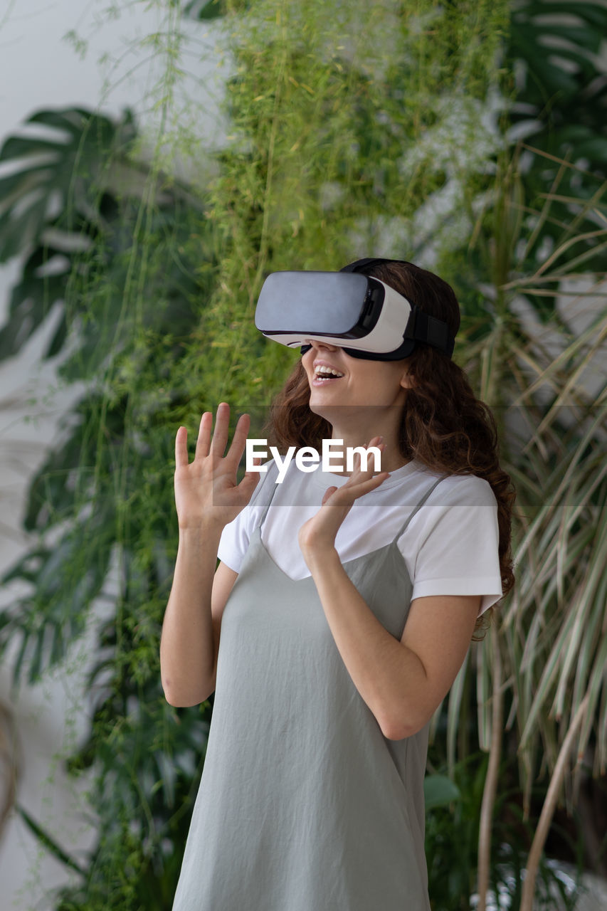 Overjoyed young woman spending leisure time in virtual reality while relaxing at home garden
