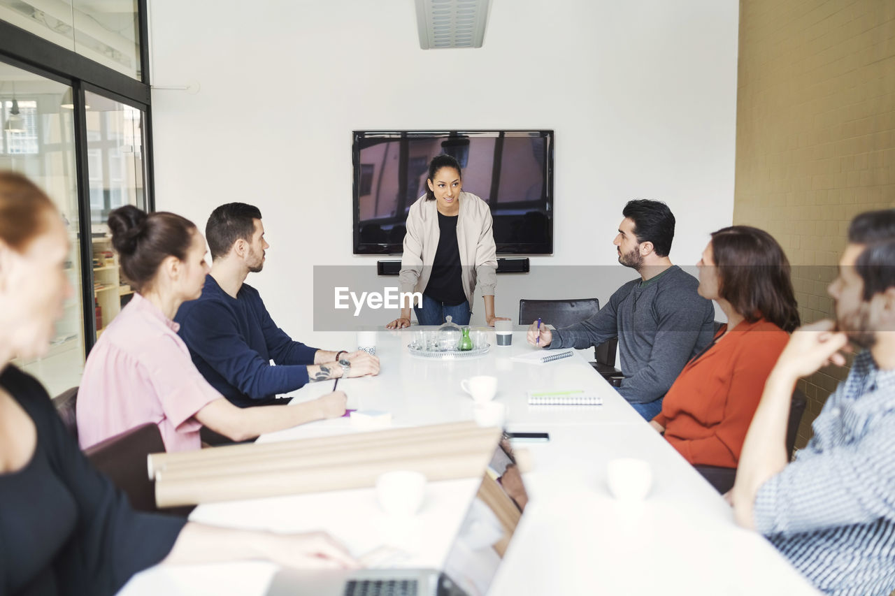 Young businesswoman giving presentation to colleagues in conference room