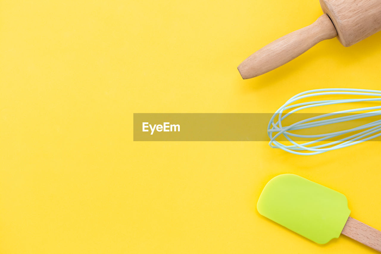 HIGH ANGLE VIEW OF HUMAN HAND HOLDING YELLOW COLORED BACKGROUND