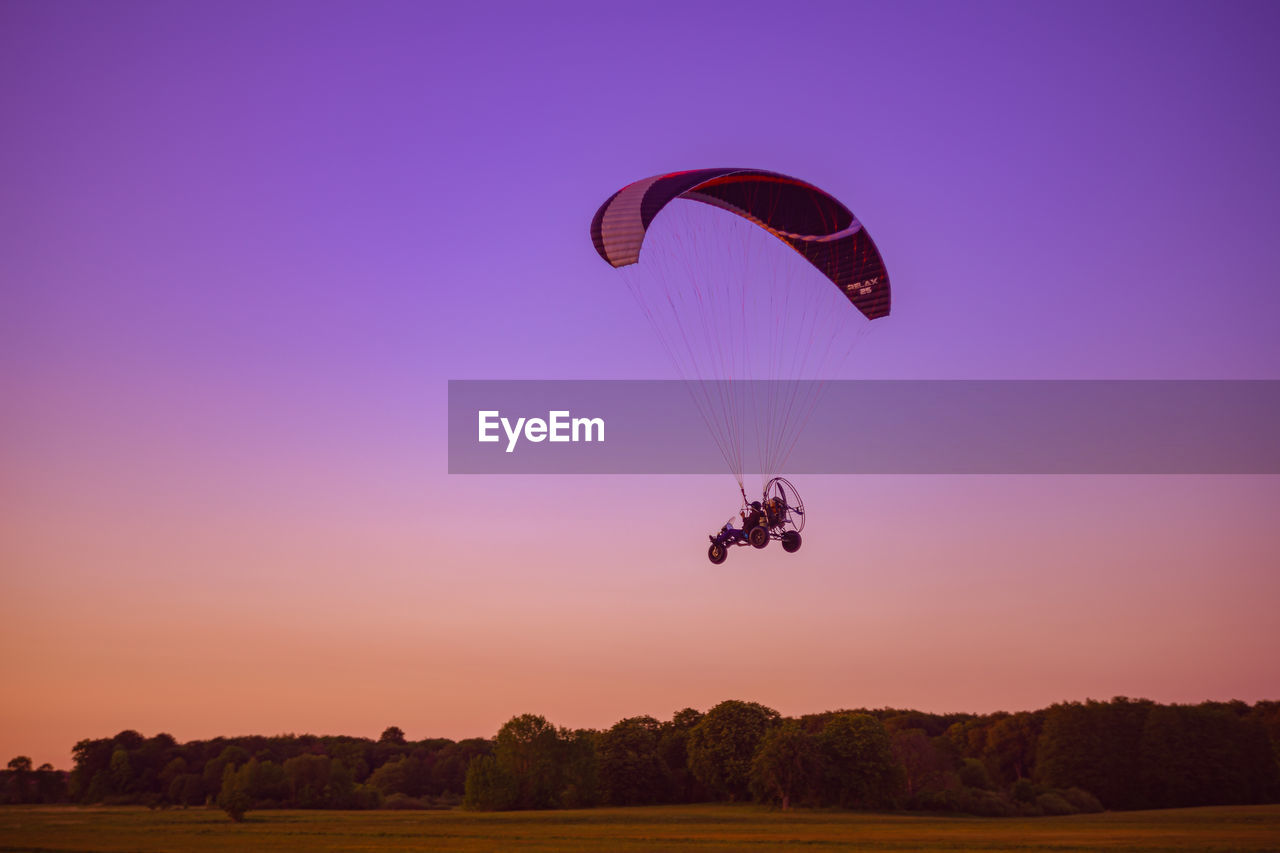 Person paragliding against sky during sunset