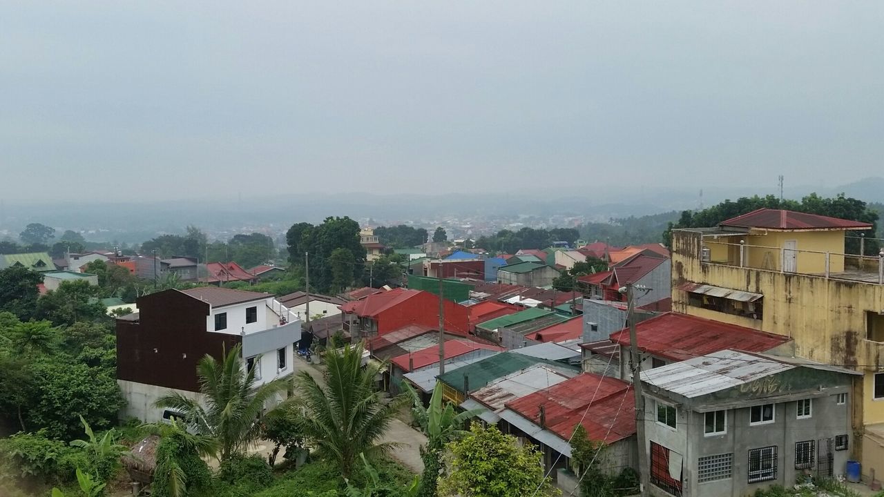 View of houses in town with mountains against foggy sky