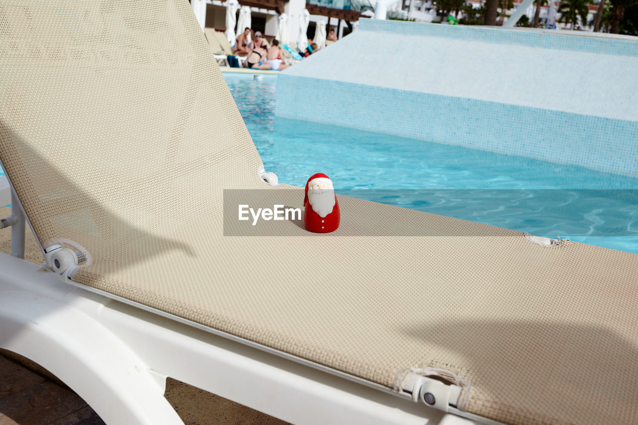 Lounge chair by swimming pool on sunny day