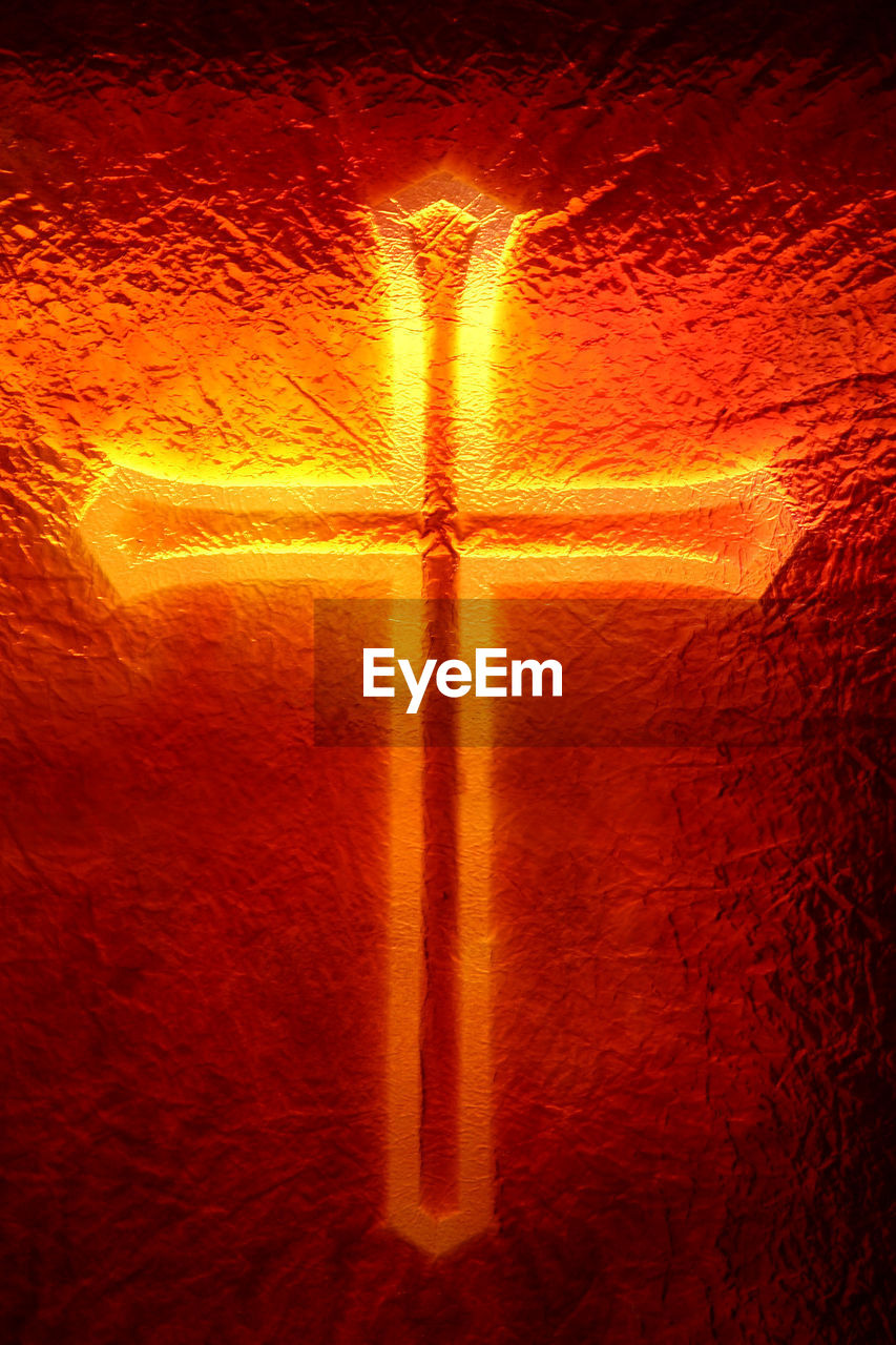 Illuminated gold cross on red frosted glass