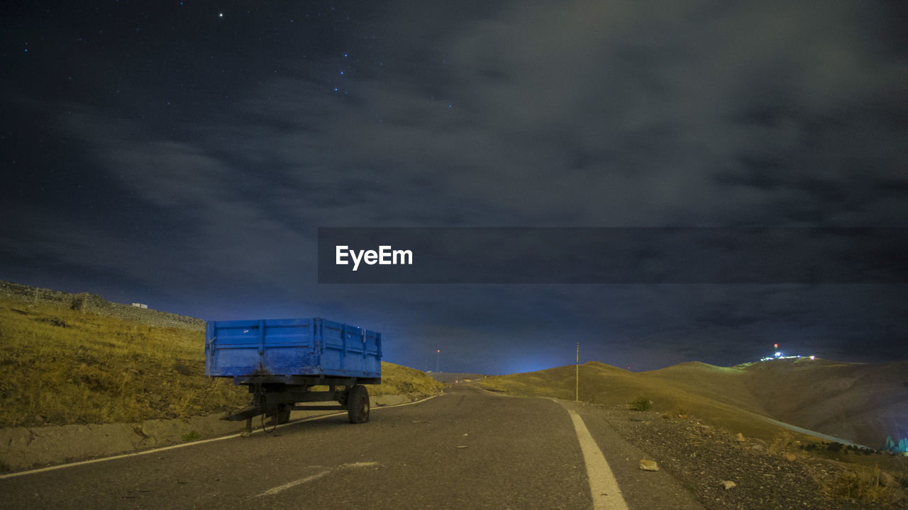 Vehicle on road against cloudy sky at night
