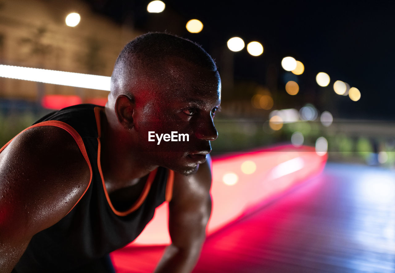 Sweaty ethnic athlete resting at night