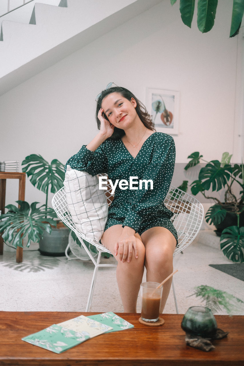 Portrait of young woman sitting on chair at cafe