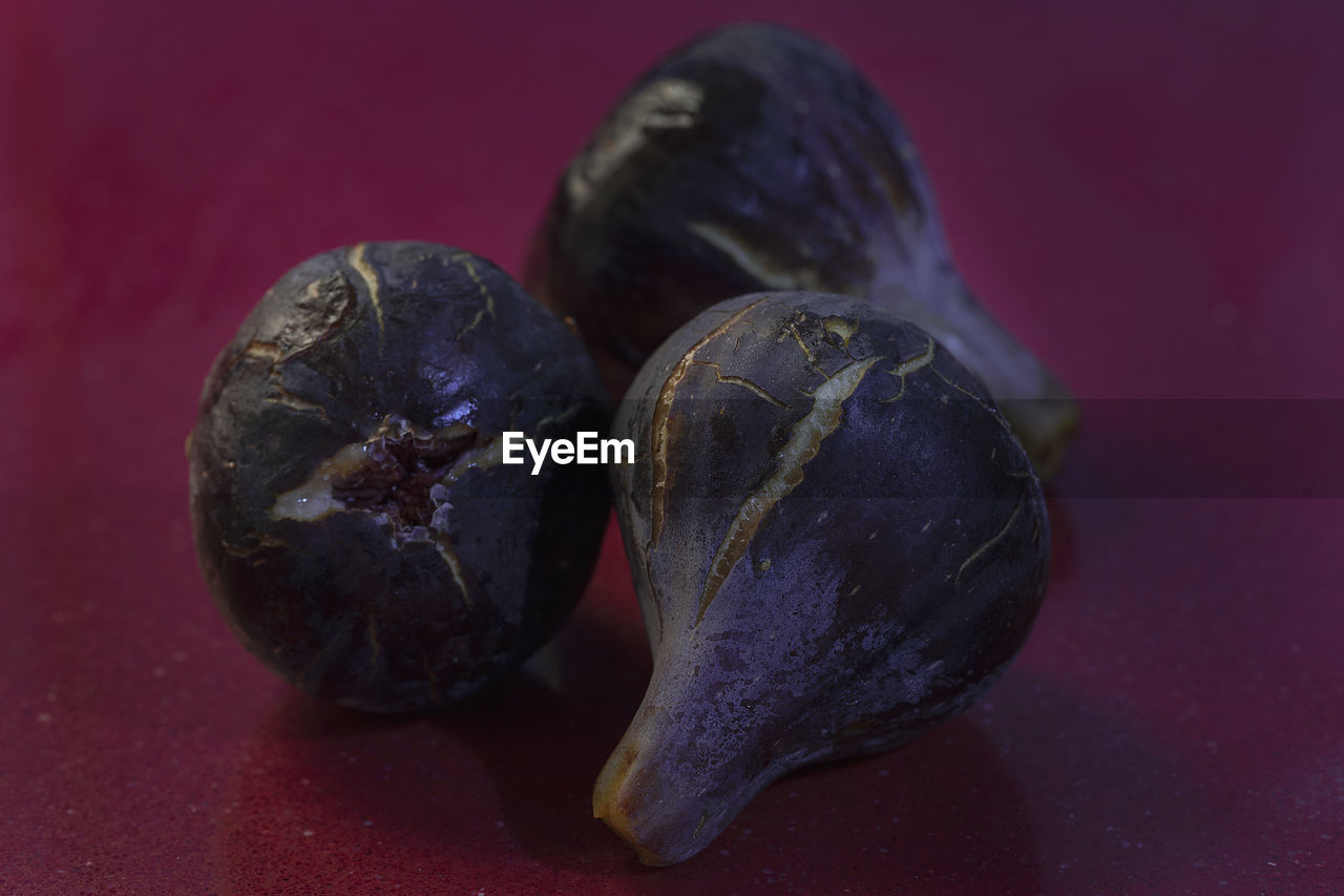Close-up of three purple figs on a red table 
