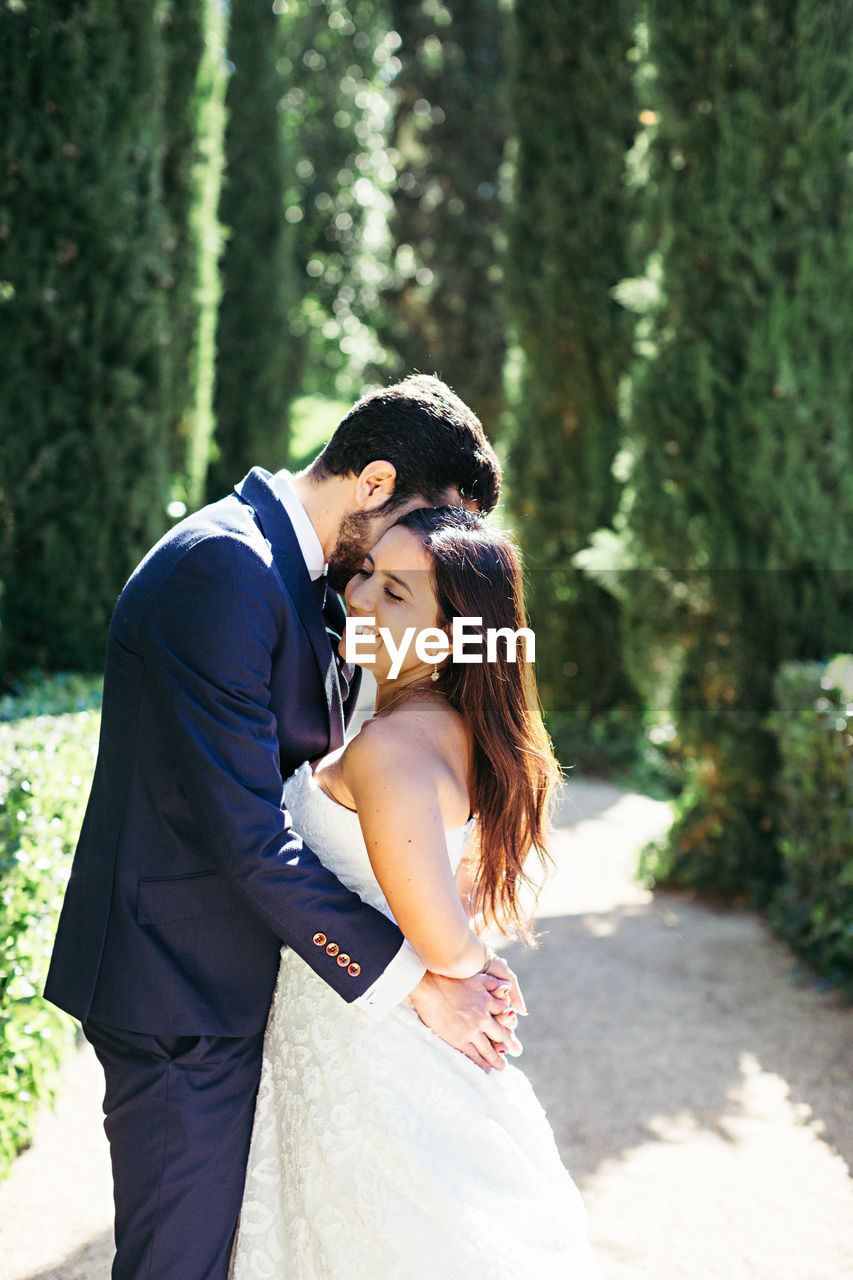 Newlywed couple romancing while standing in park