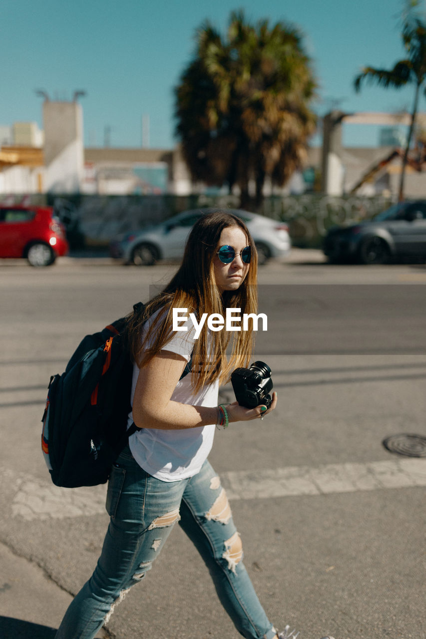 YOUNG WOMAN WEARING SUNGLASSES ON ROAD