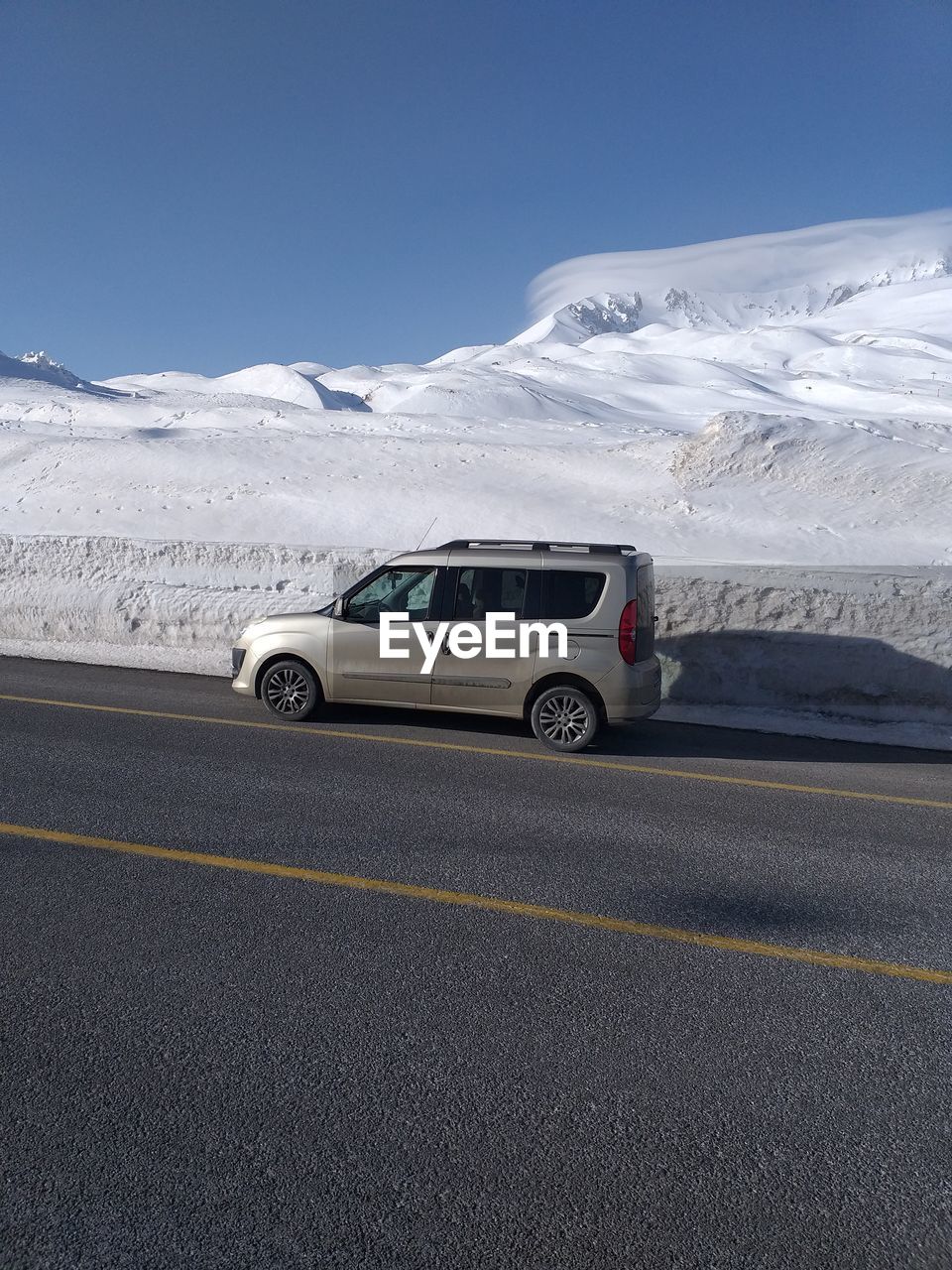 CARS ON ROAD AGAINST SNOWCAPPED MOUNTAIN