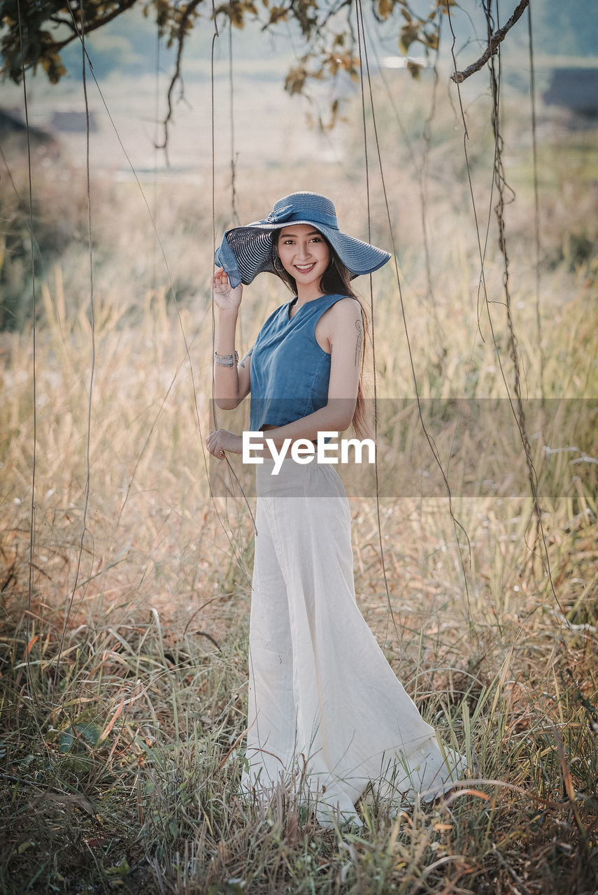 Portrait of smiling young woman standing on grassy field