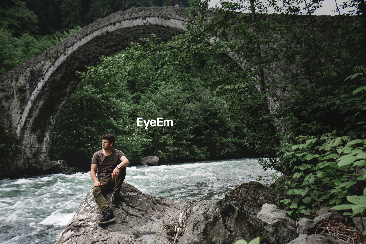 Man standing on rock by river