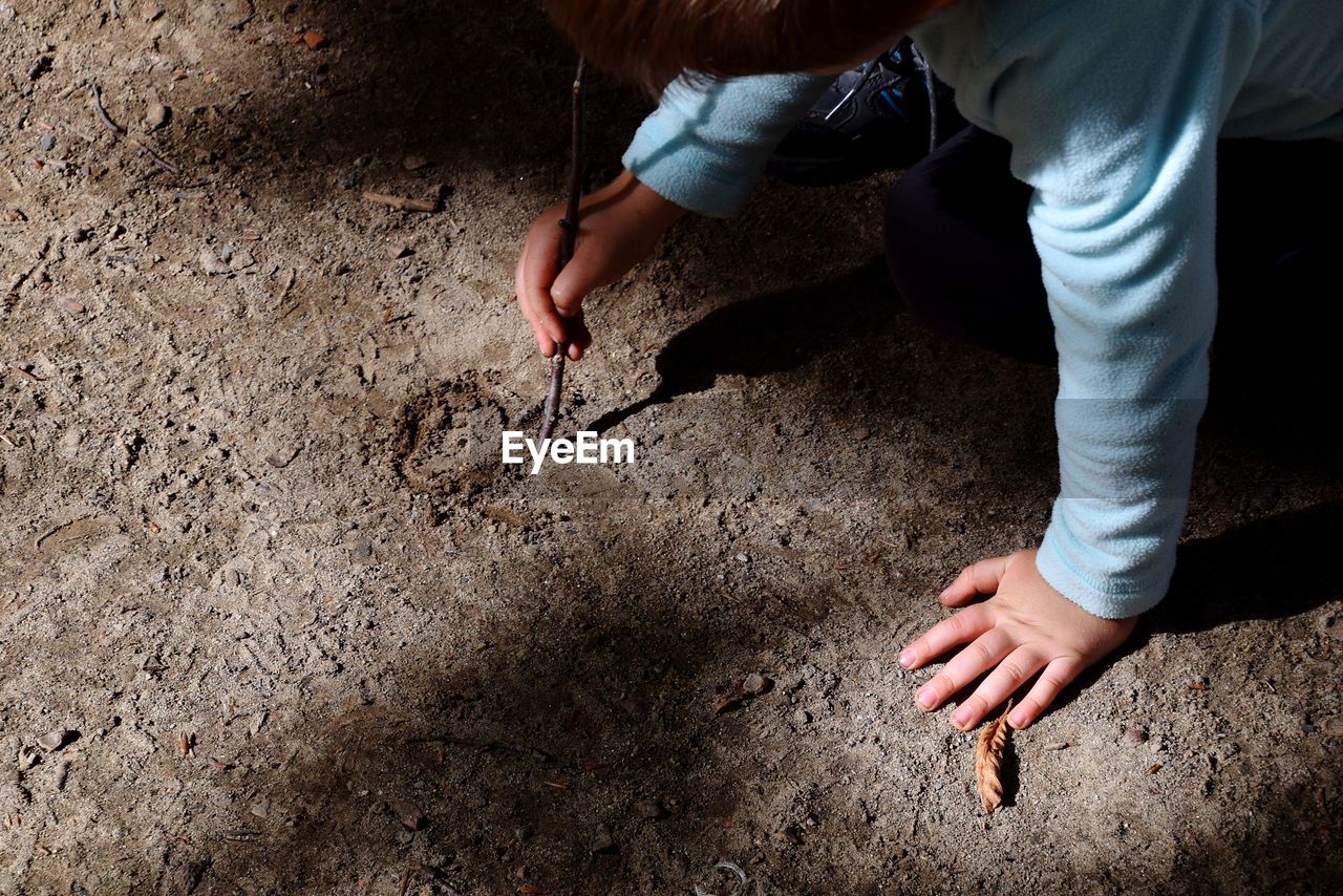 Midsection of child writing on sand