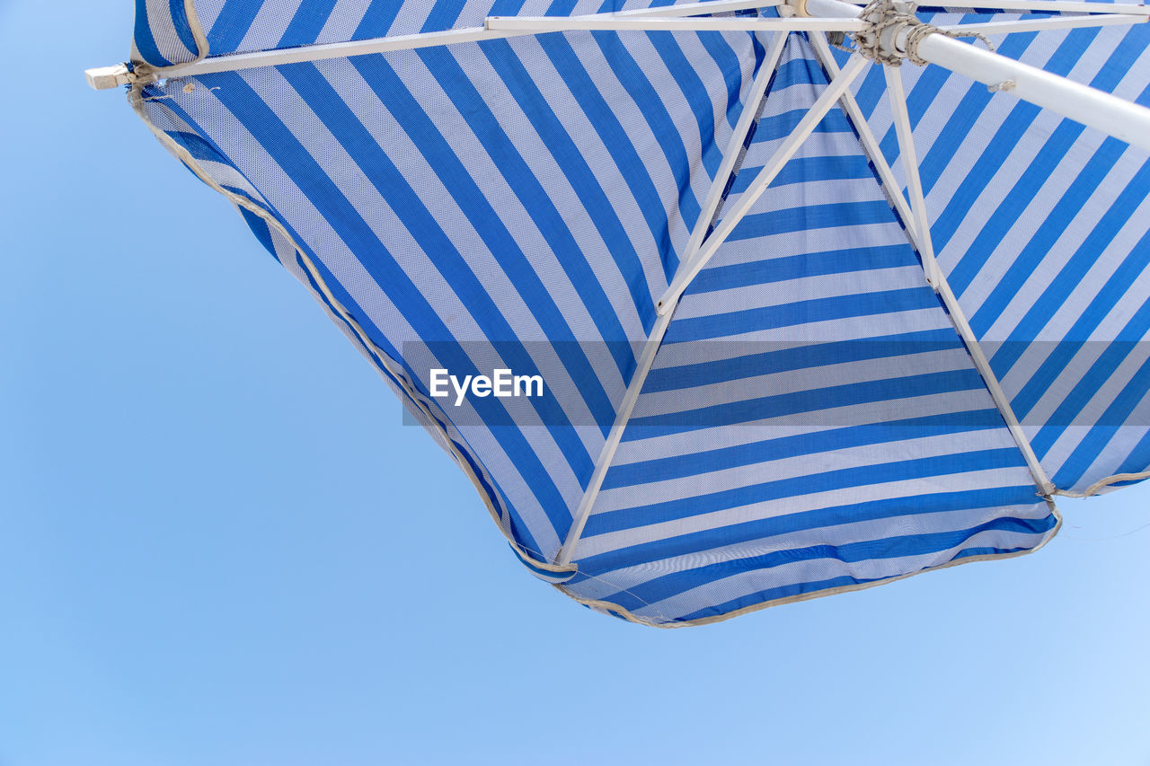 Low angle view of beach umbrella against clear blue sky