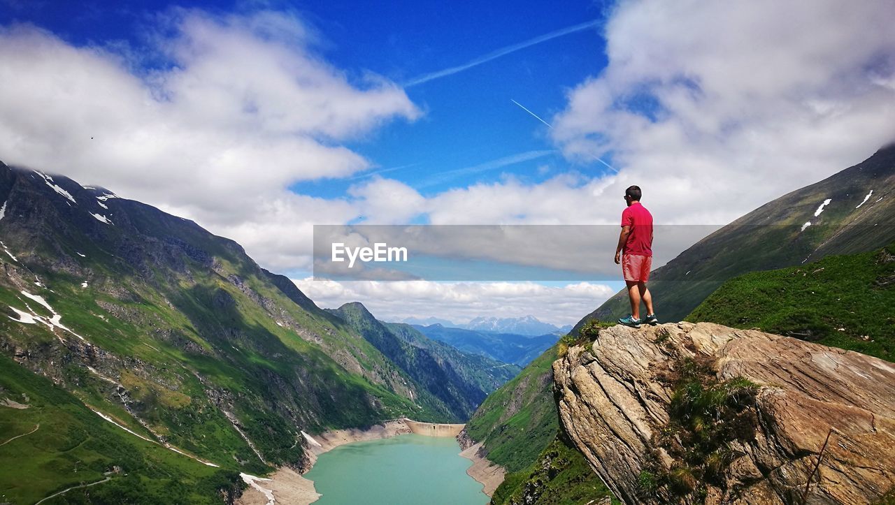 Rear view of man standing on mountain against sky