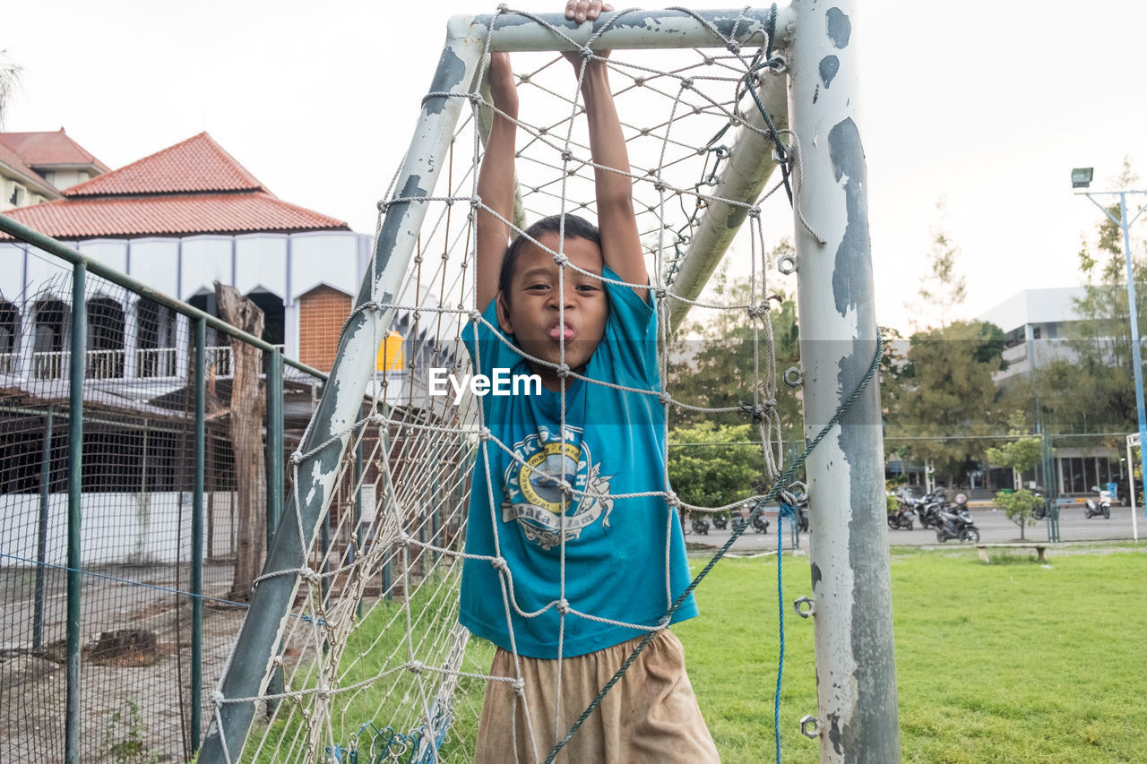 Portrait of boy hanging on fence