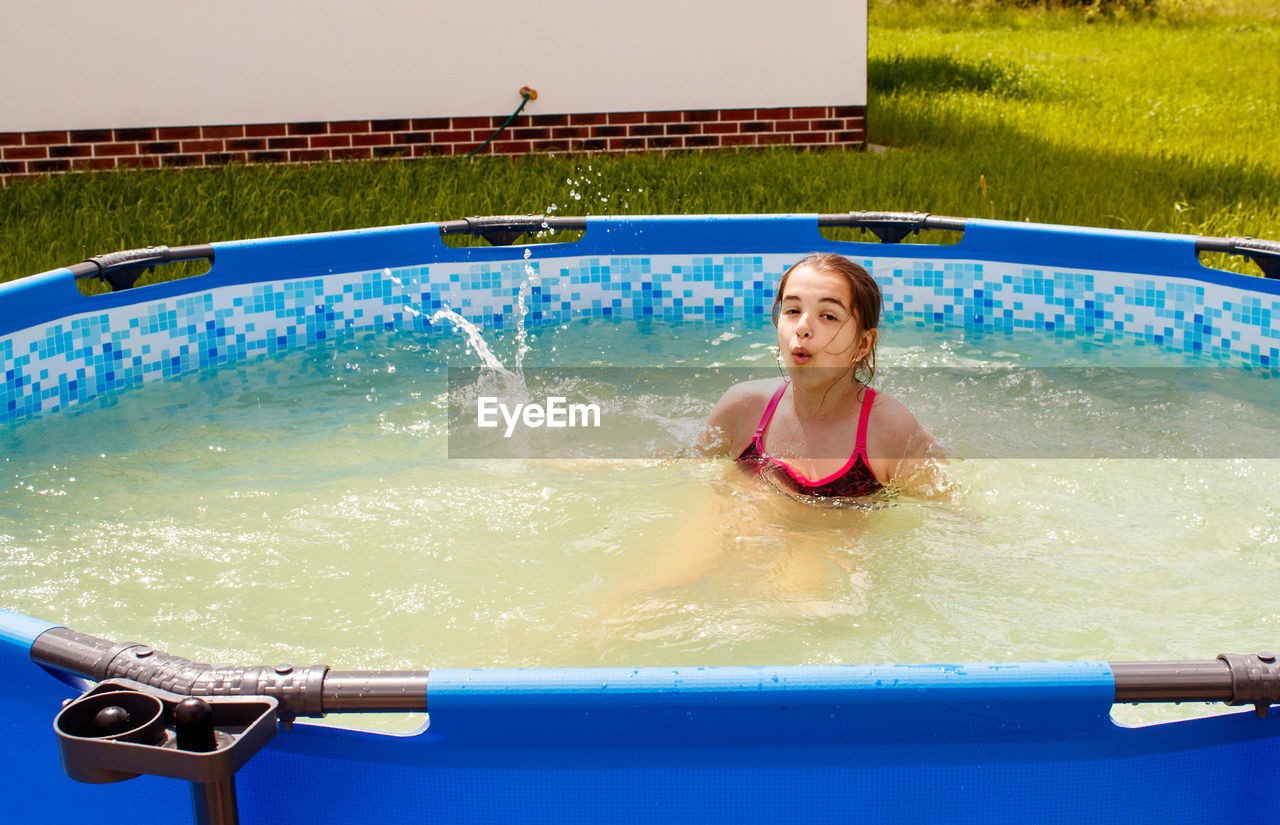 Portrait of smiling girl in wading pool outdoors