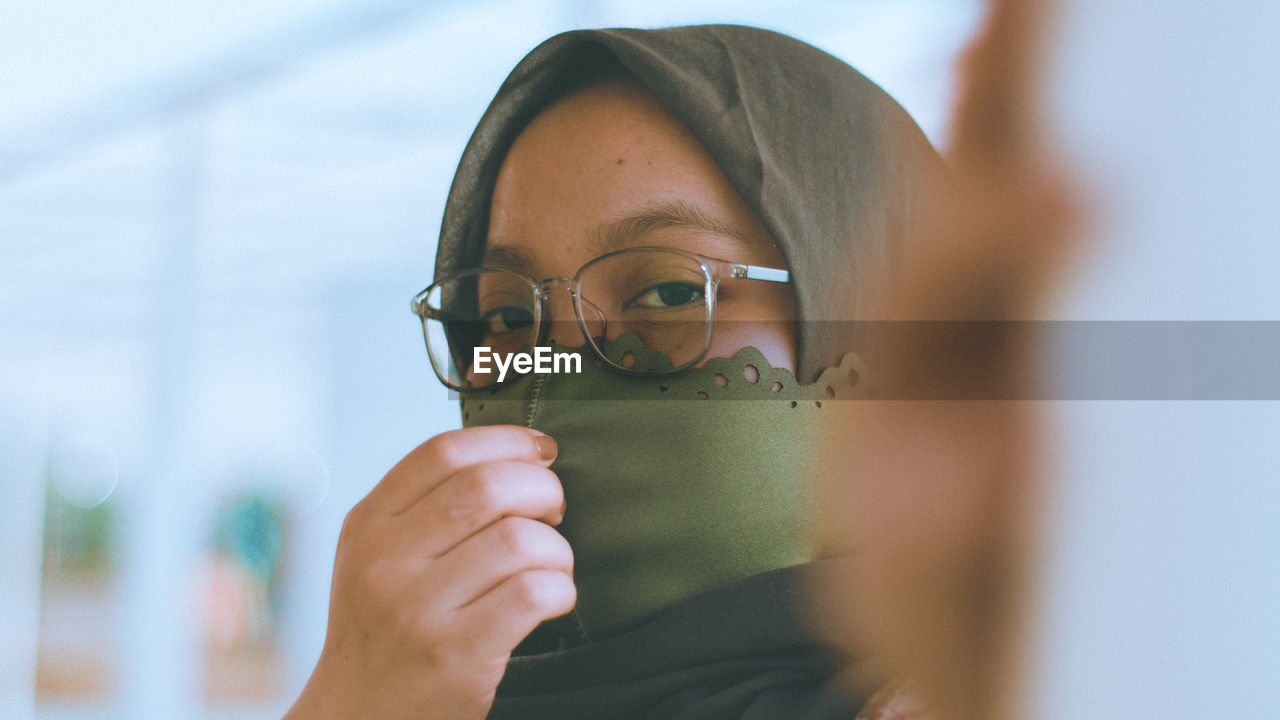 Close-up portrait of young woman holding eyeglasses