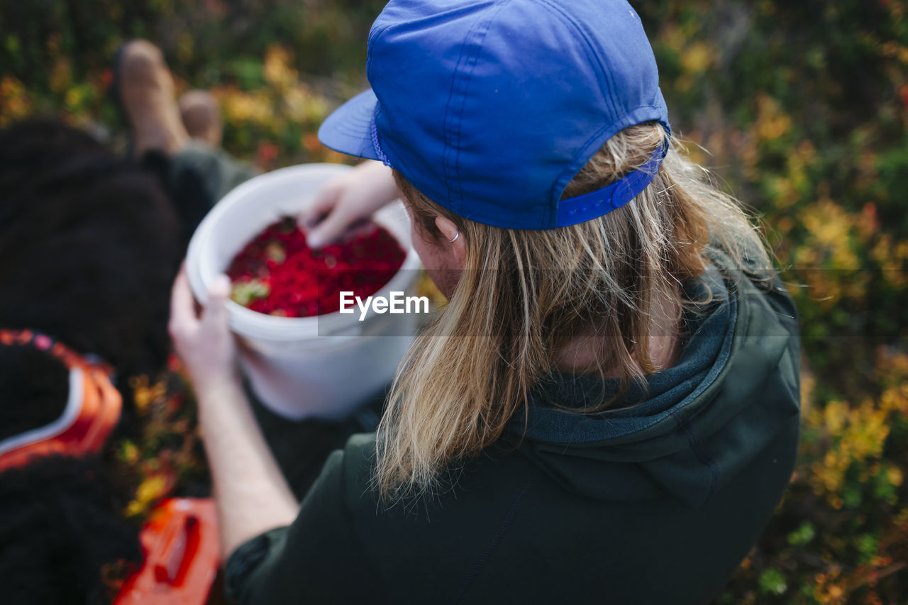 Man holding bucket full of lingonberries