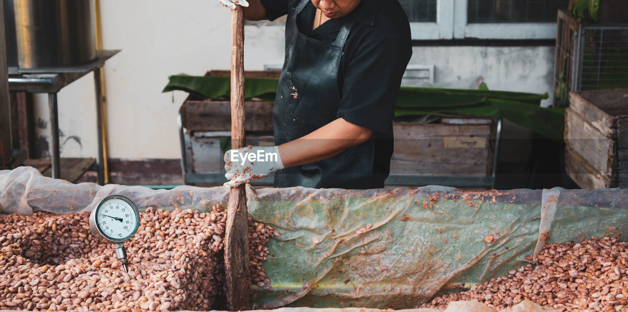 Midsection of man working with cocoa seeds at factory