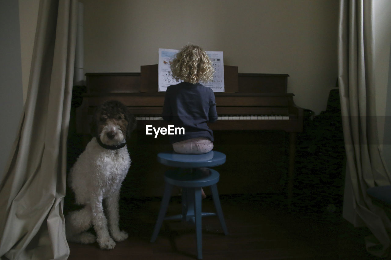 Boy sitting by girl playing piano at home