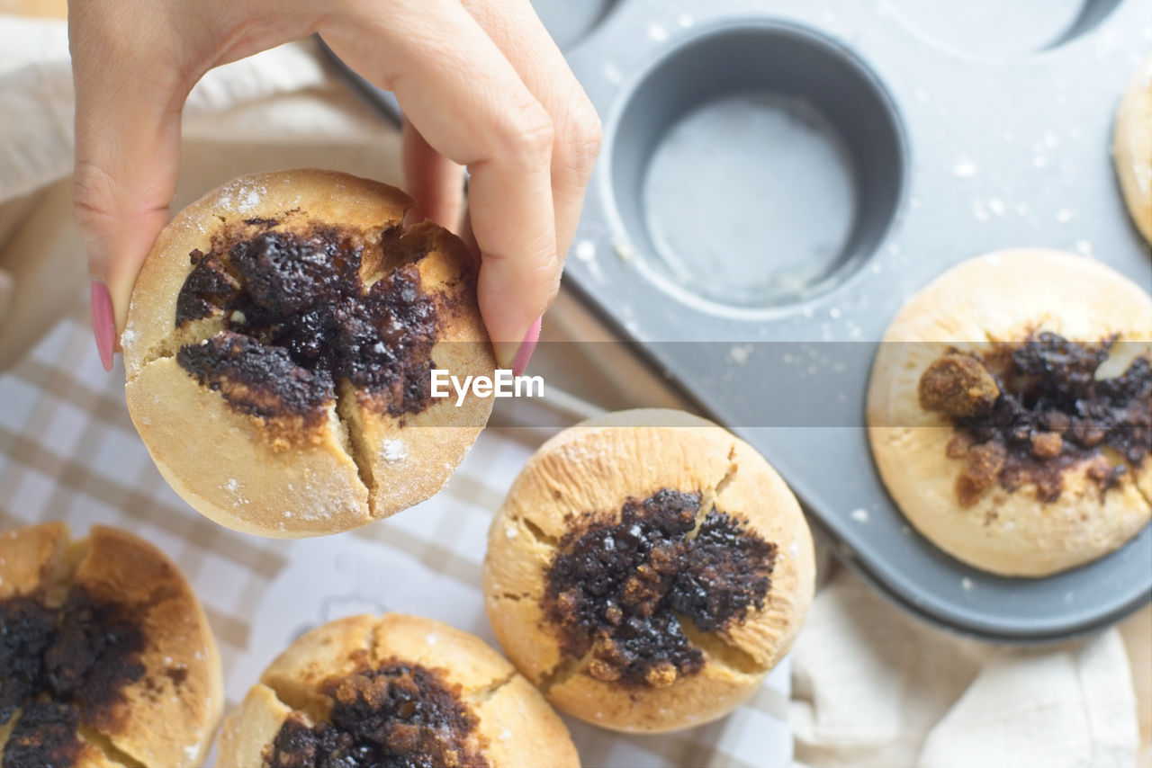 Cropped hand of woman picking muffins from tin 