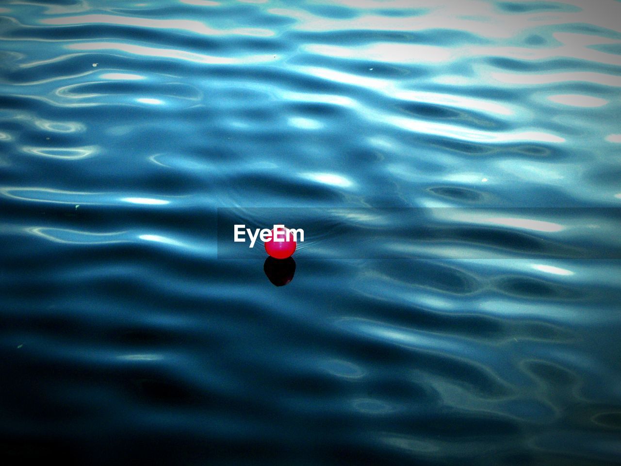 High angle view of red balloon floating on lake