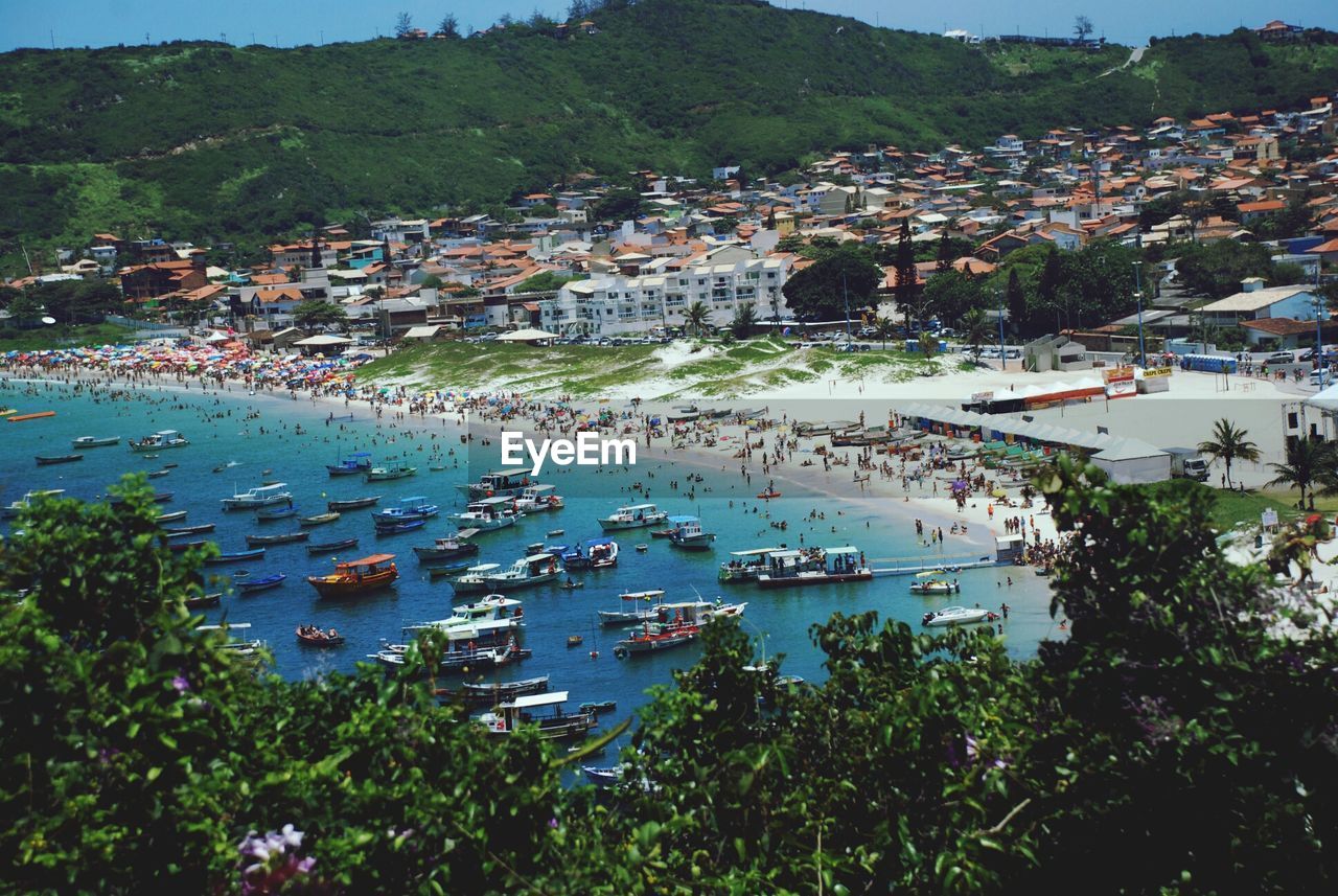 Elevated view of seaside town with crowded beach and boats in harbor