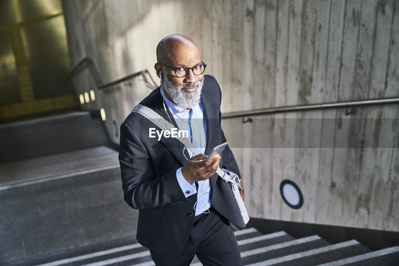 Businessman with crossbody bag using smartphone