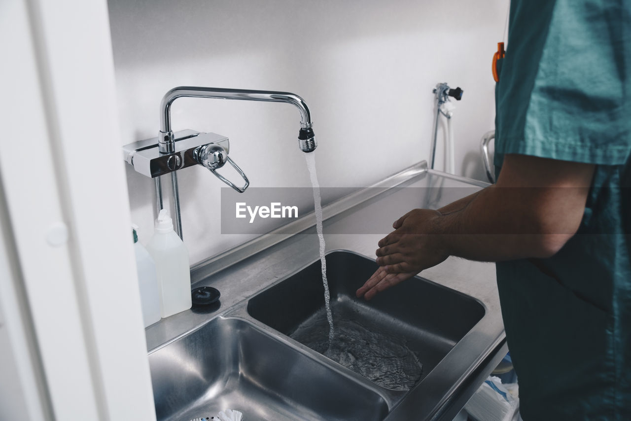 Cropped image of male nurse washing hands in sink at hospital