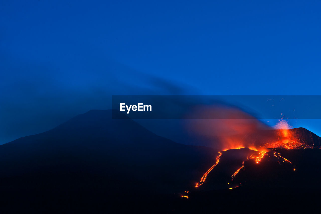 View of volcano erupting at night