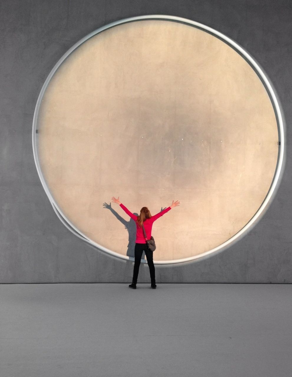 Woman with arms outstretched against round wall