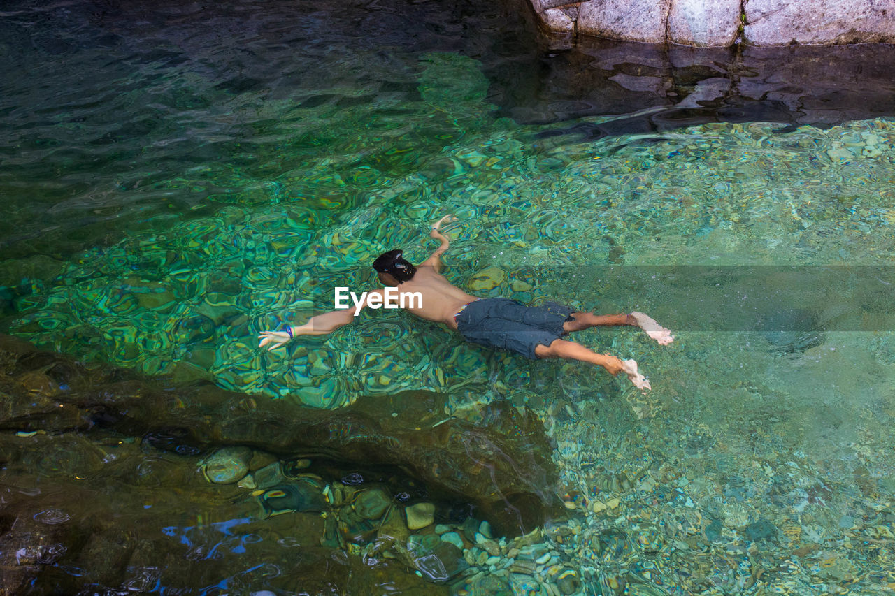 High angle view of shirtless man swimming in sea