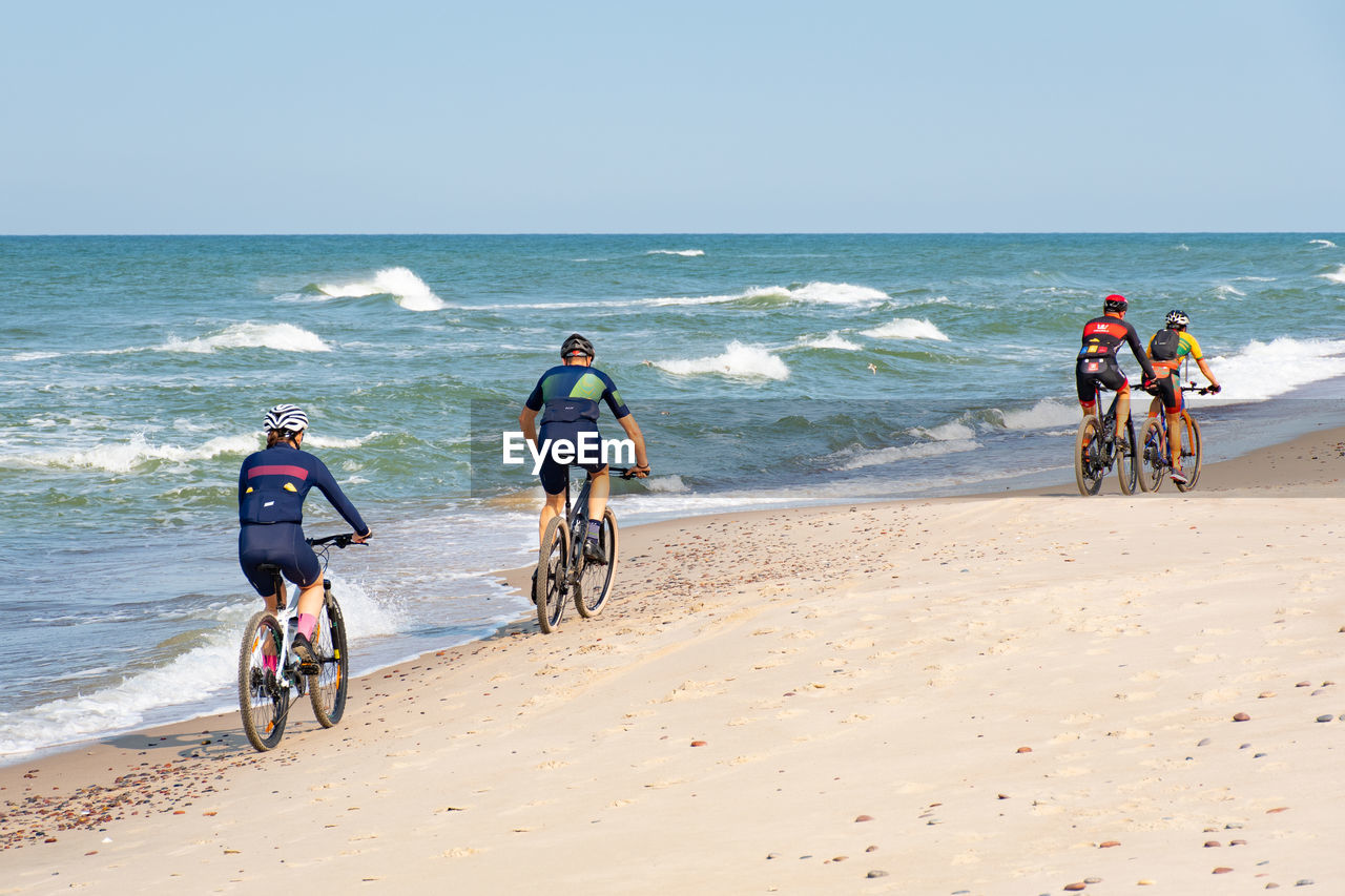 PEOPLE RIDING BICYCLES ON BEACH