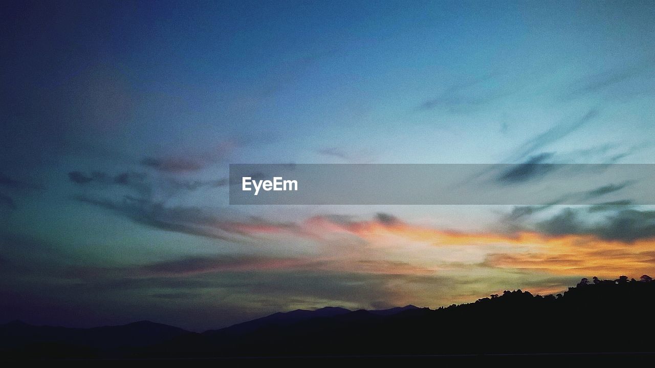 SCENIC VIEW OF SILHOUETTE MOUNTAINS AGAINST BLUE SKY