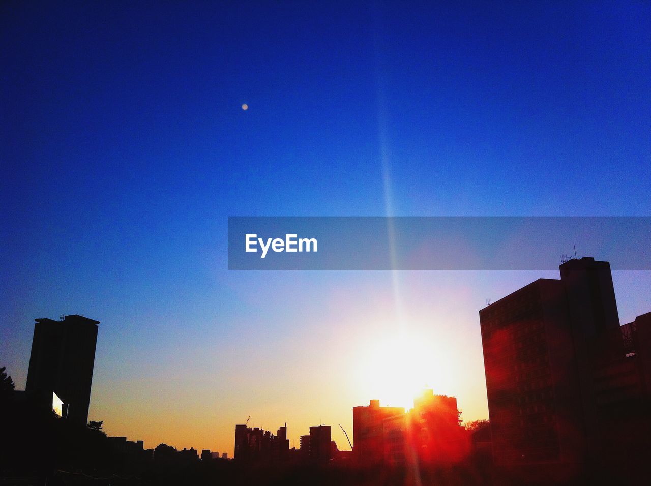 Silhouette buildings against blue sky during sunset