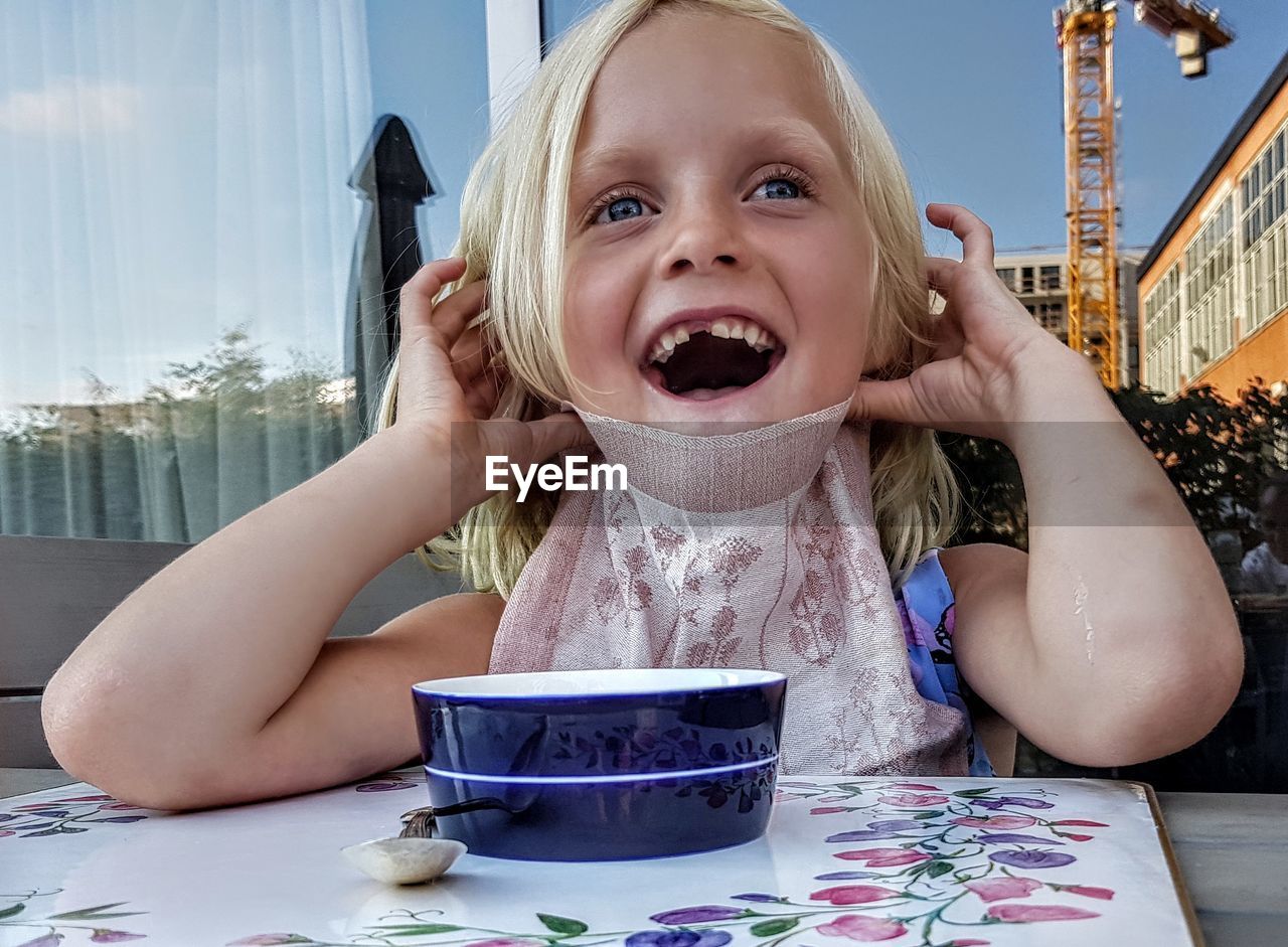 Shocked girl having food in bowl at table