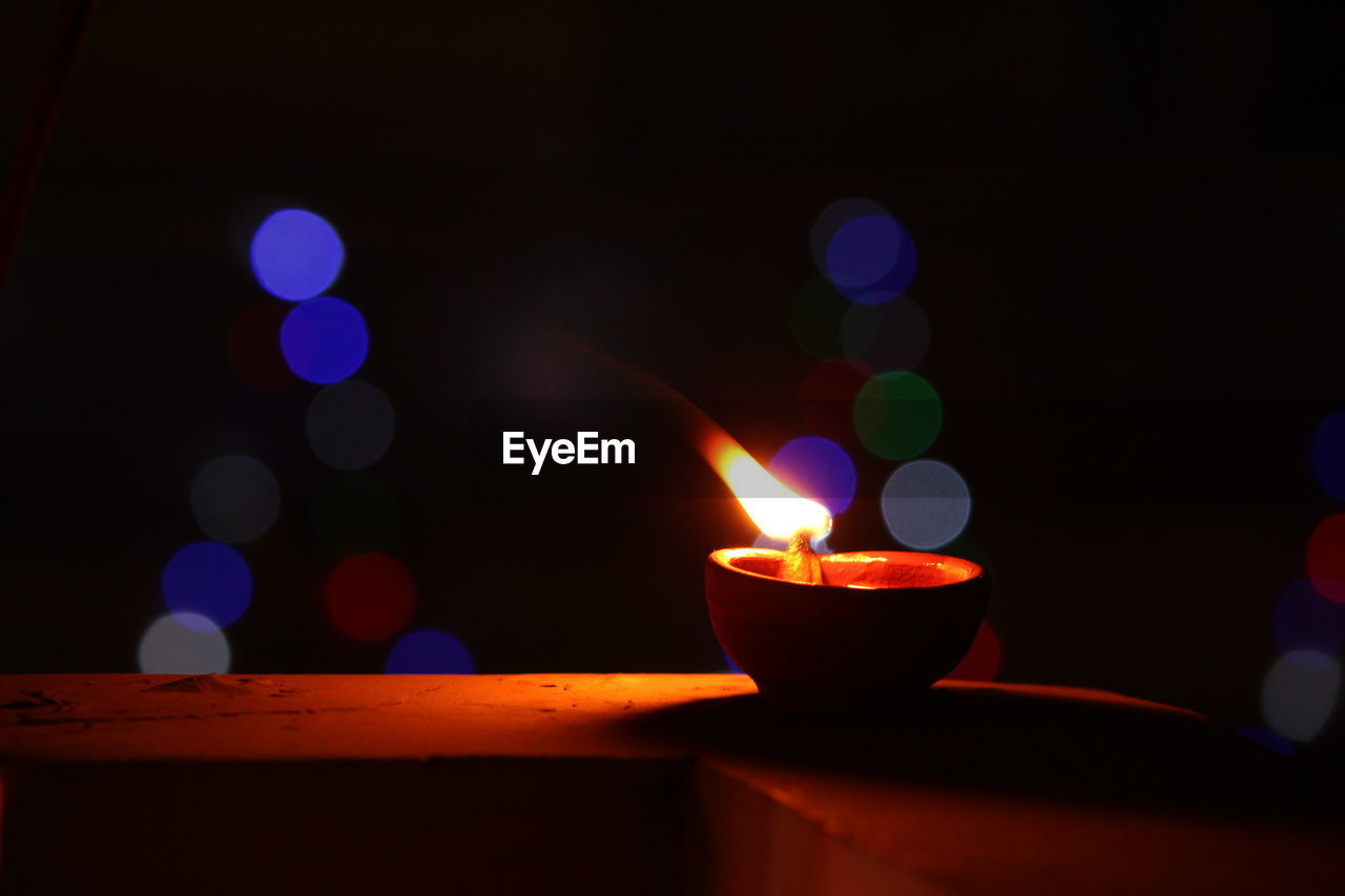 Close-up of illuminated diya on retaining wall