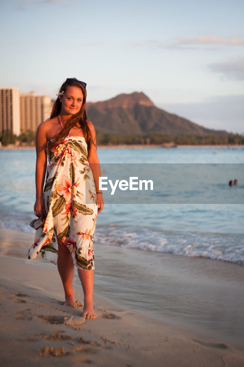 Full length portrait of young woman standing at beach