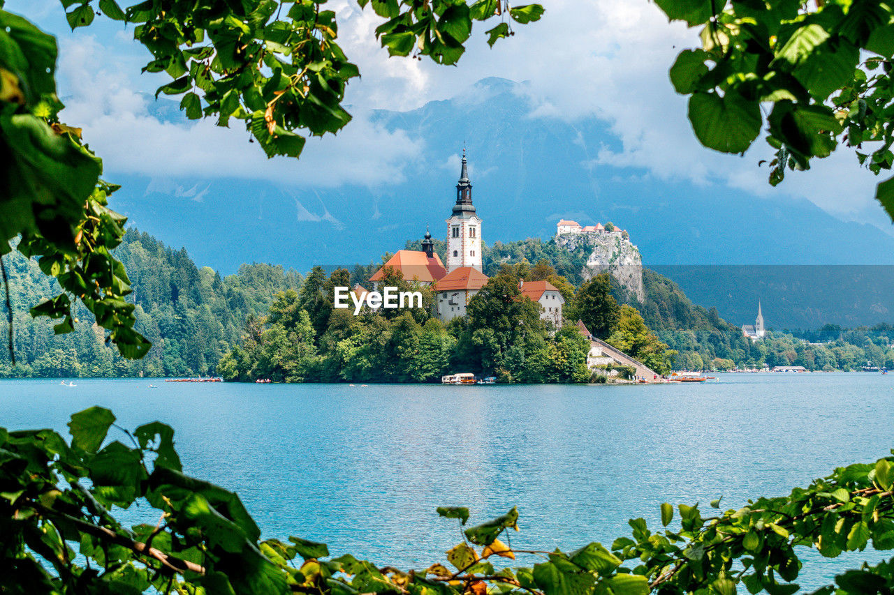 Amazing view on bled lake, island,church and castle framed by the leaves of the trees
