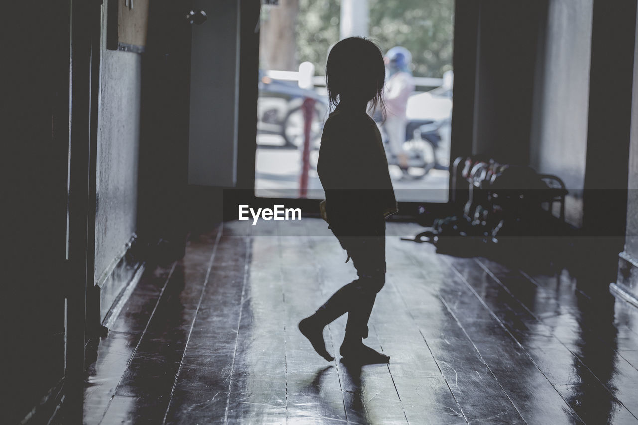 Side view of silhouette woman standing on floor at home