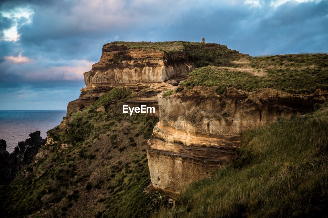 SCENIC VIEW OF ROCK FORMATIONS BY SEA AGAINST SKY