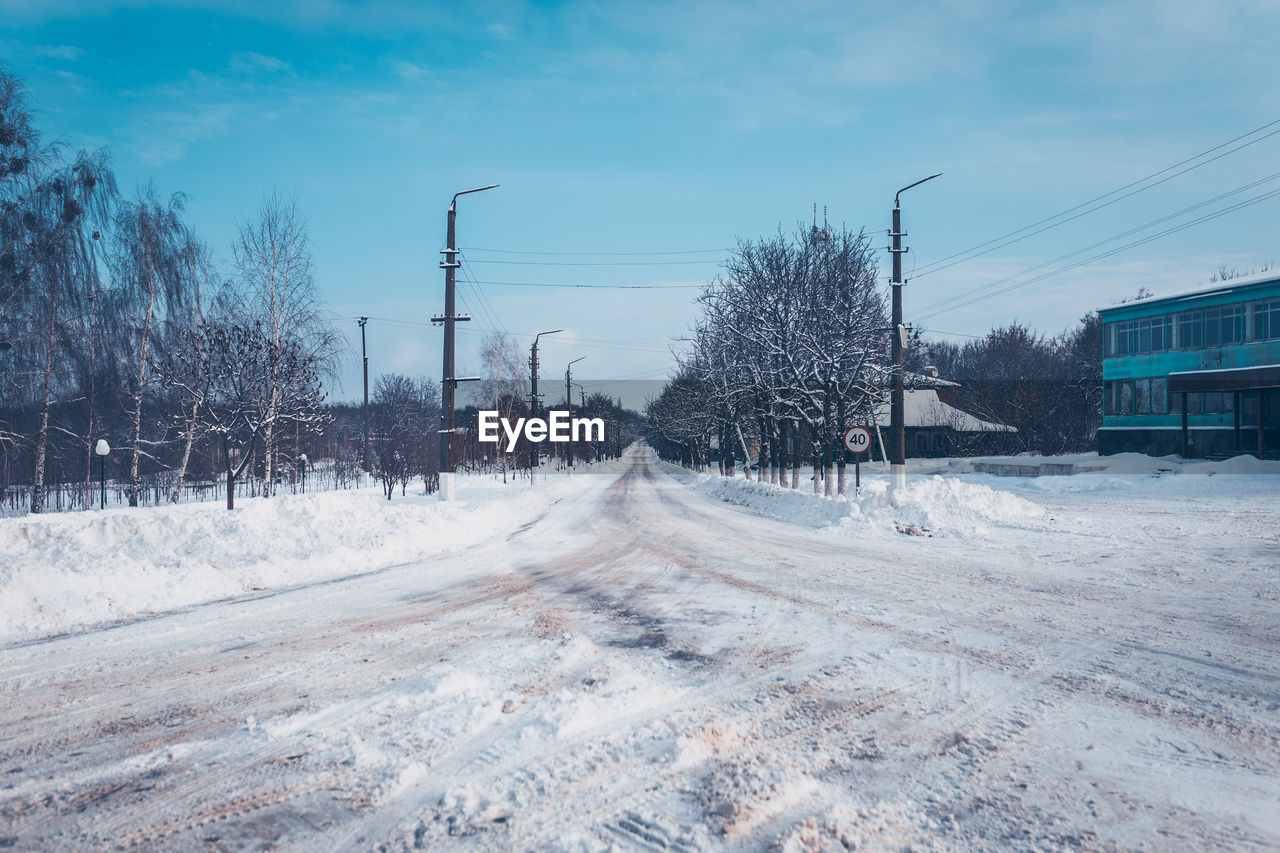 ROAD AMIDST SNOW COVERED TREES AGAINST SKY