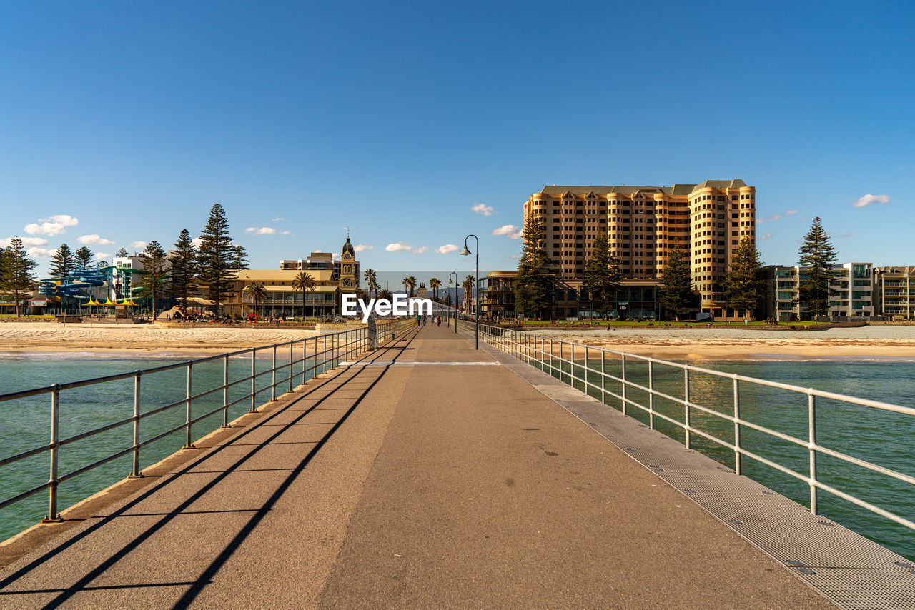 FOOTPATH BY SWIMMING POOL AGAINST BUILDINGS IN CITY AGAINST CLEAR SKY