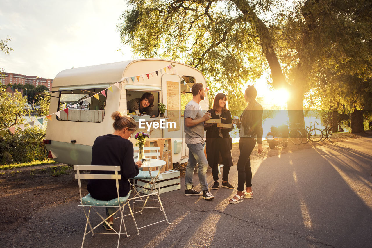 Owner looking at customers standing on street through food truck window