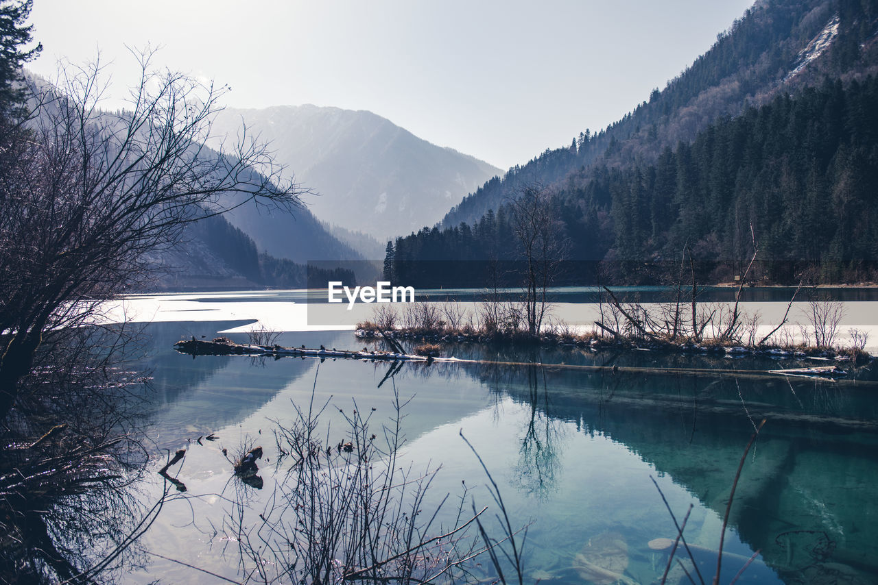 reflection, water, tree, winter, scenics - nature, lake, mountain, beauty in nature, nature, plant, tranquility, tranquil scene, environment, snow, sky, cold temperature, landscape, no people, forest, reservoir, body of water, land, morning, mountain range, non-urban scene, travel destinations, outdoors, day, travel, pinaceae, wilderness, idyllic, coniferous tree, pine tree, tourism, pine woodland